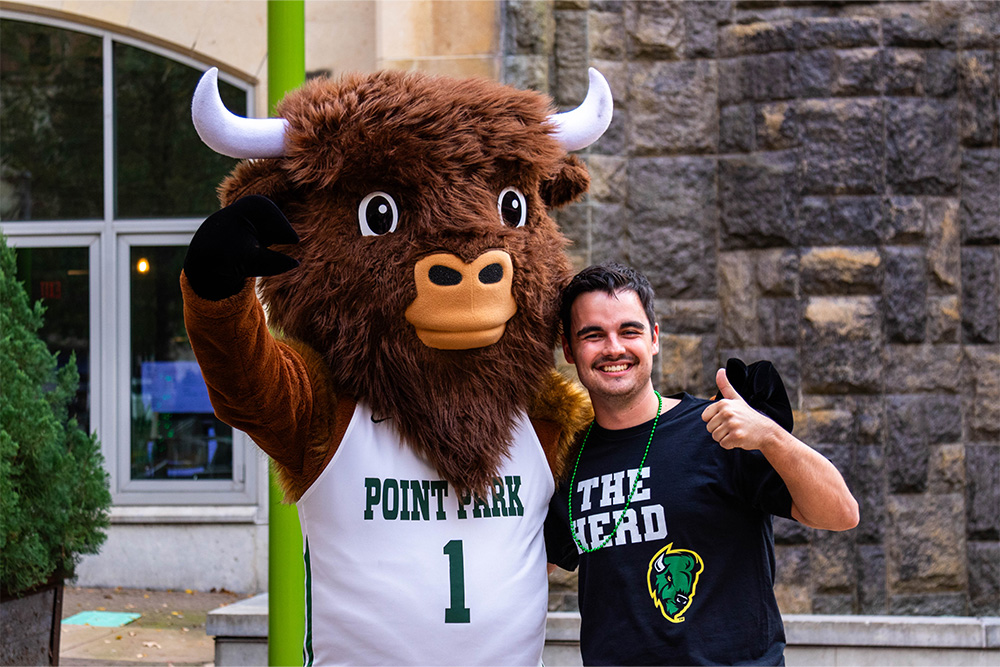 A male student poses with Black Diamond Two, the bison mascot of Point Park University.