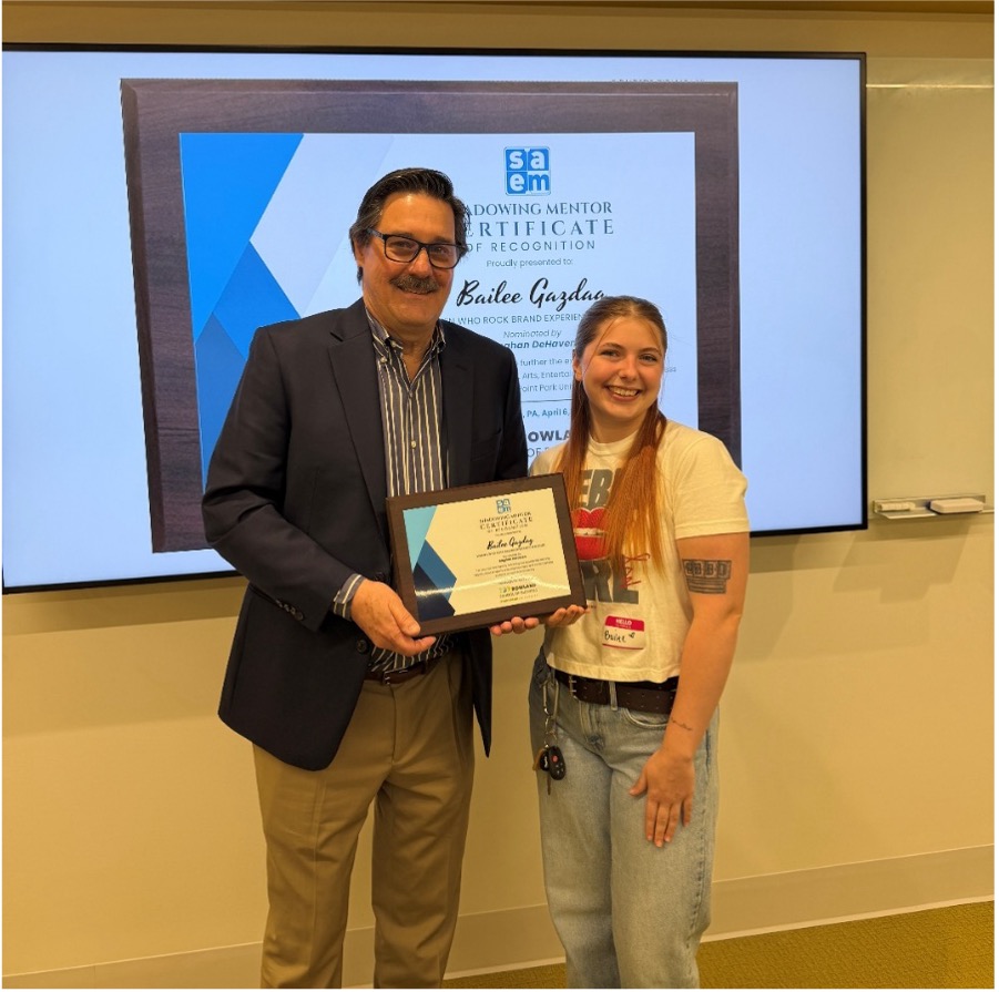 Bob Derda, left, poses with Bailee Gazdag, right, from Women Who Rock, as he presents an award for the shadowing experience.