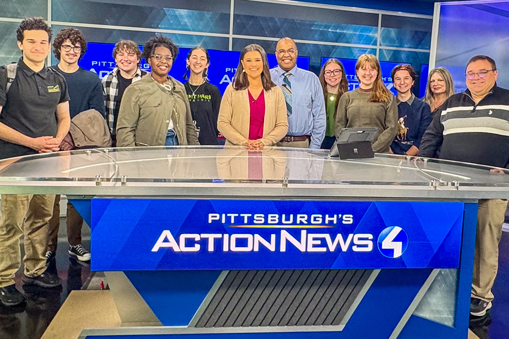 Students, faculty and alumni gather around the news desk for the news station WTAE. 