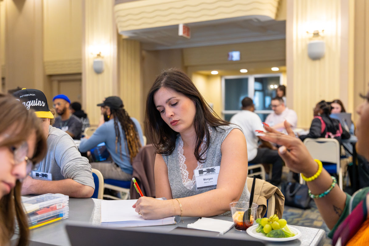 Morgan Barba writes in a notebook at a table in the workshop.