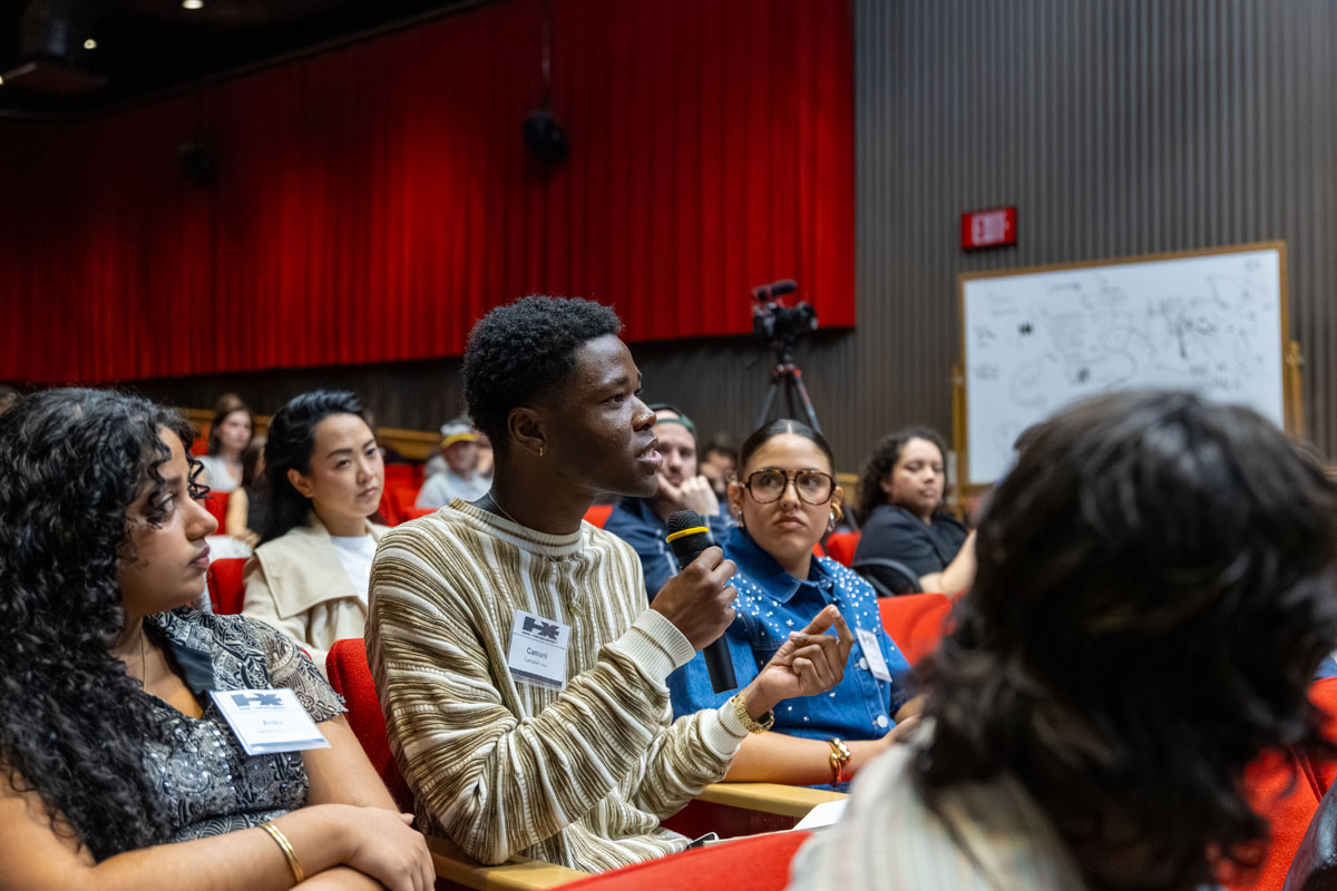 A male student in the audience asks a question into a microphone.