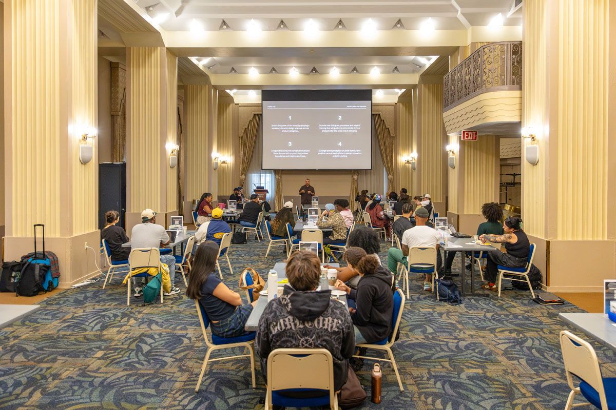 Students sit at tables in the ballroom. 