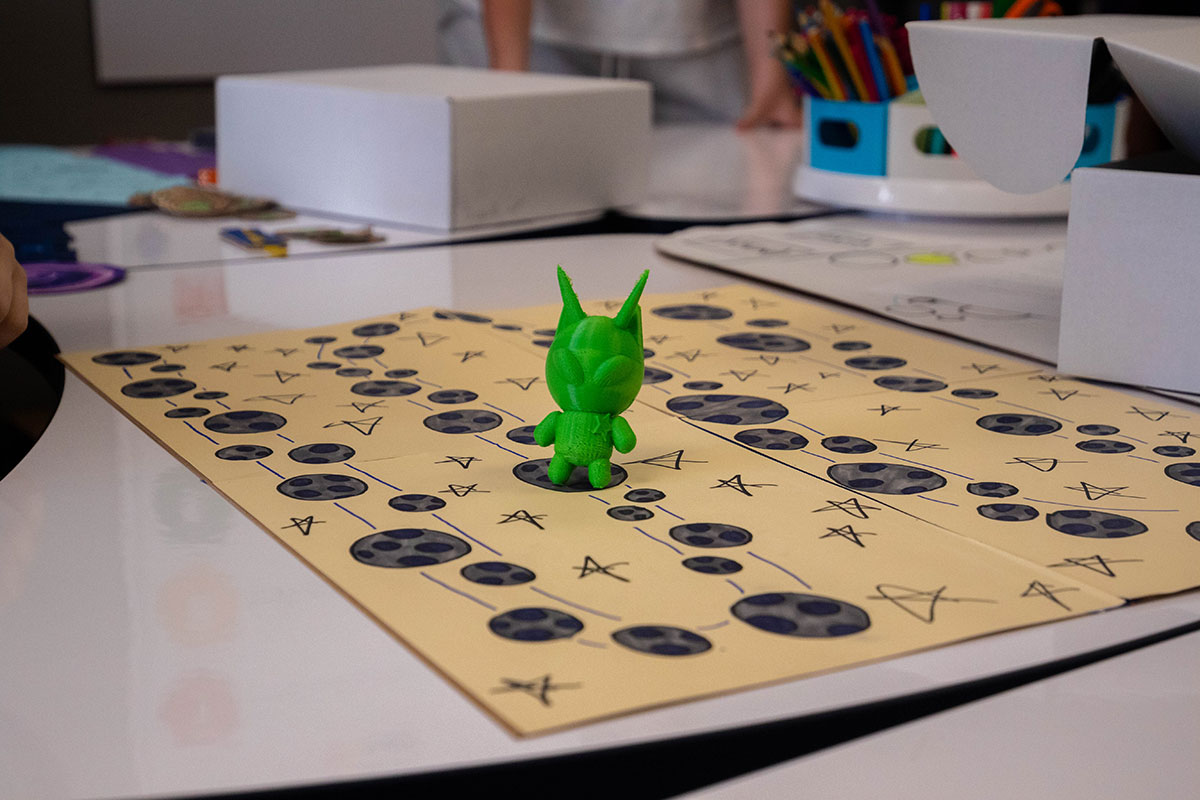 A close up photo of a board and a 3-D printed alien.