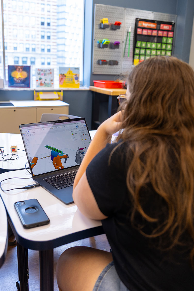 A student designs a 3-D piece on their laptop.