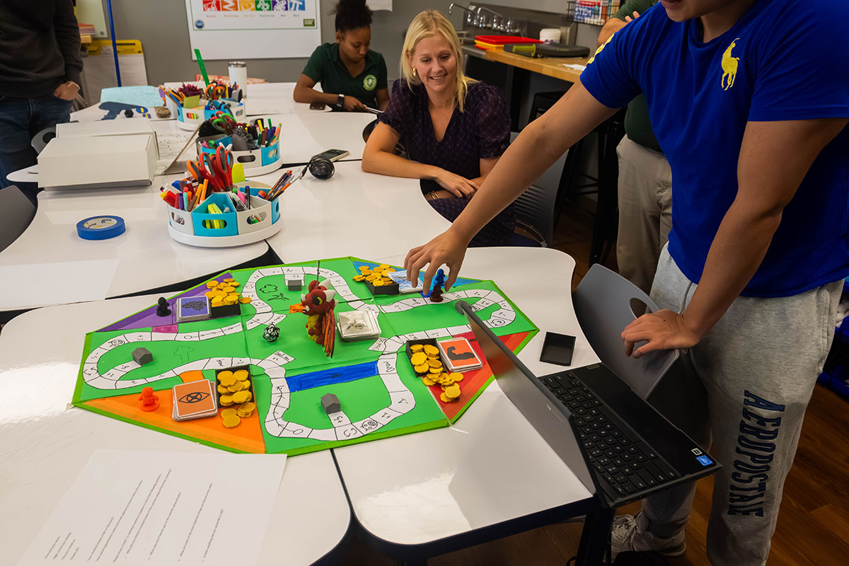 A student demonstrates game play on his board game.