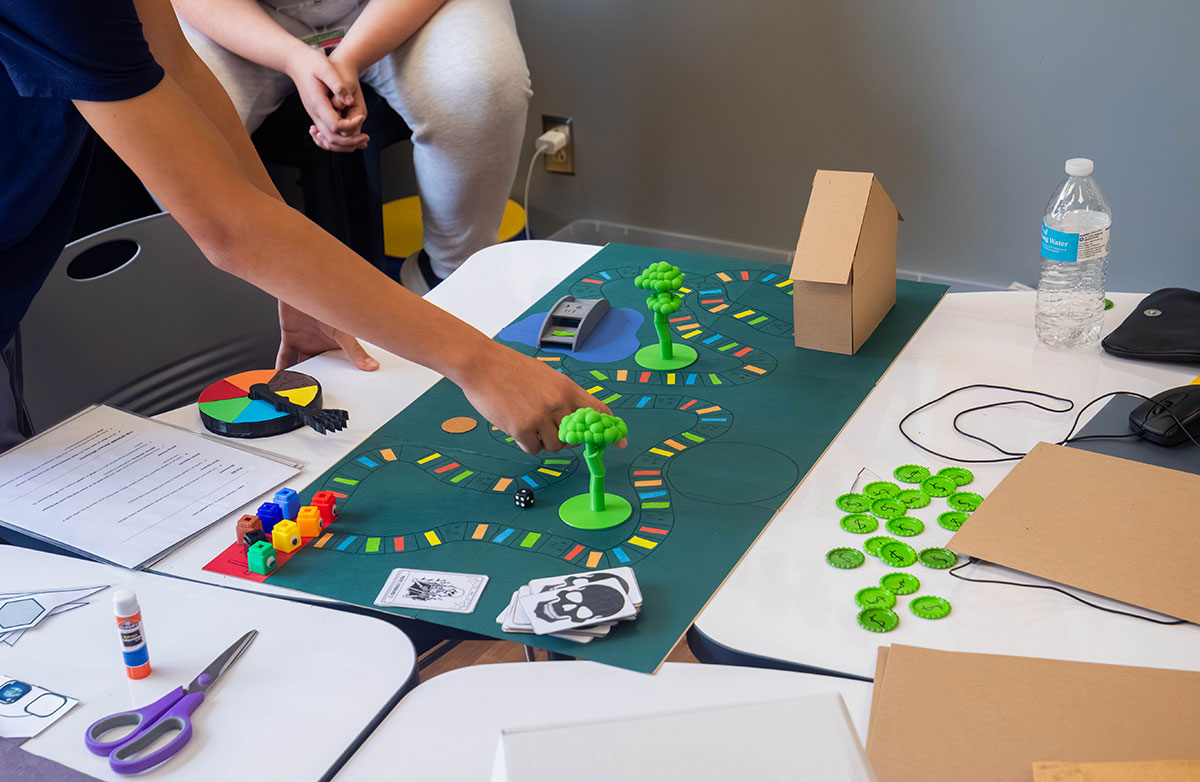 A student demonstrates game play on his board game.