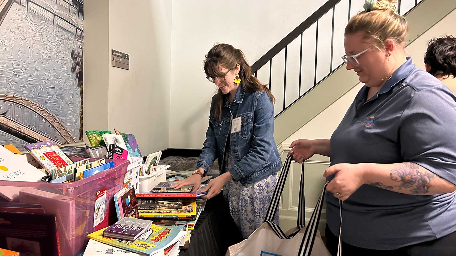 A student fills a bag held by a woman with supplies for the classroom.