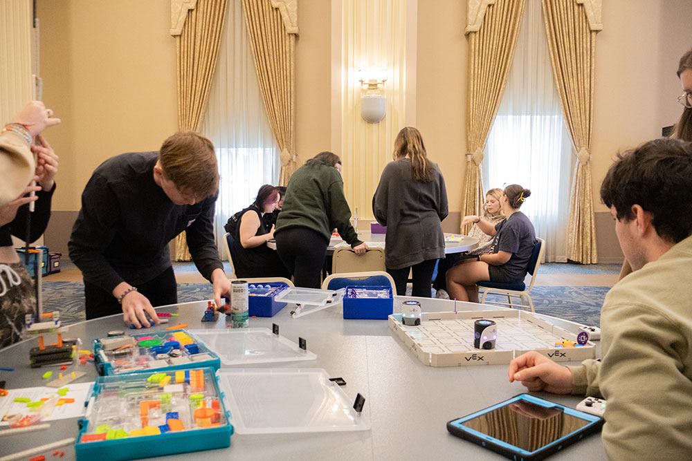 Students work with various robotics at tables.