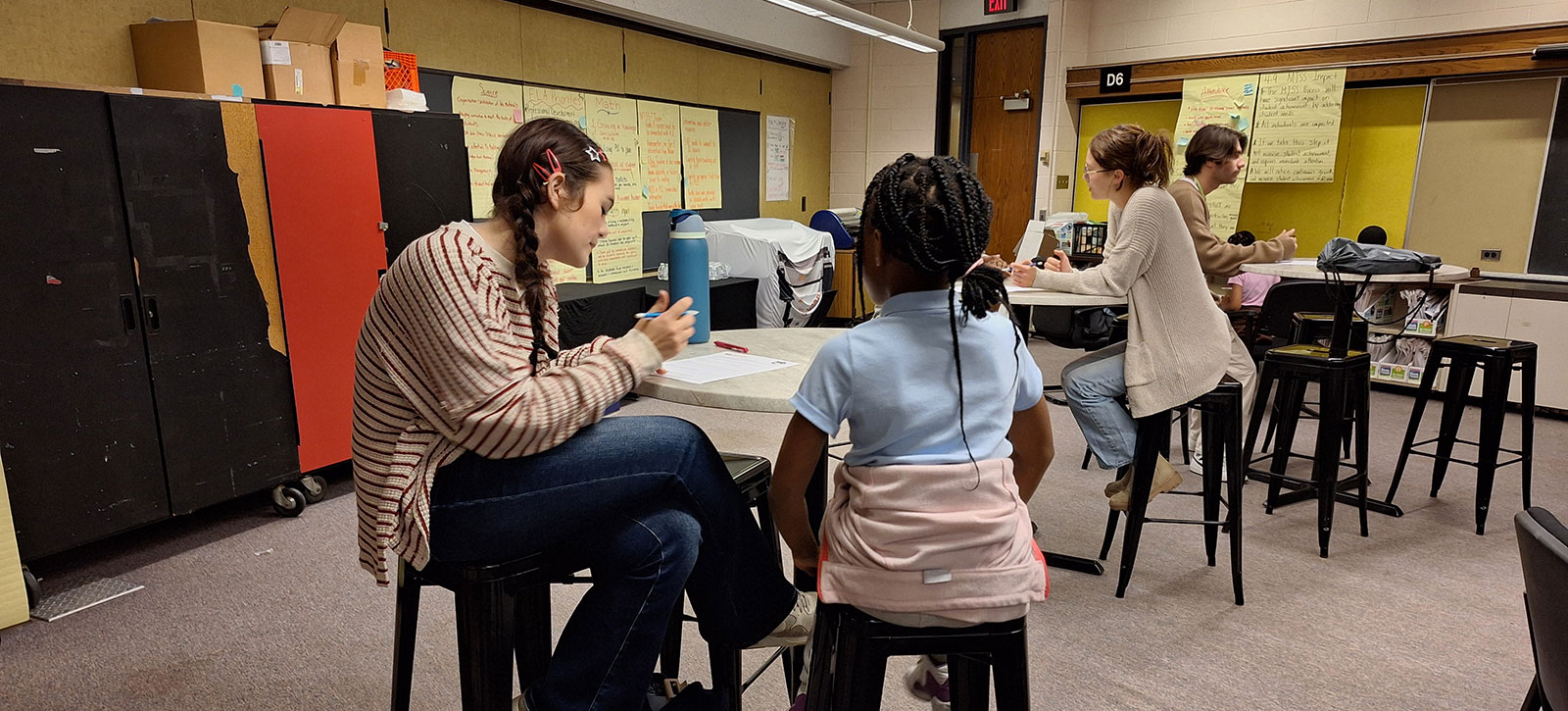 Point Park students sit at high tables with elementary students and tutor them.