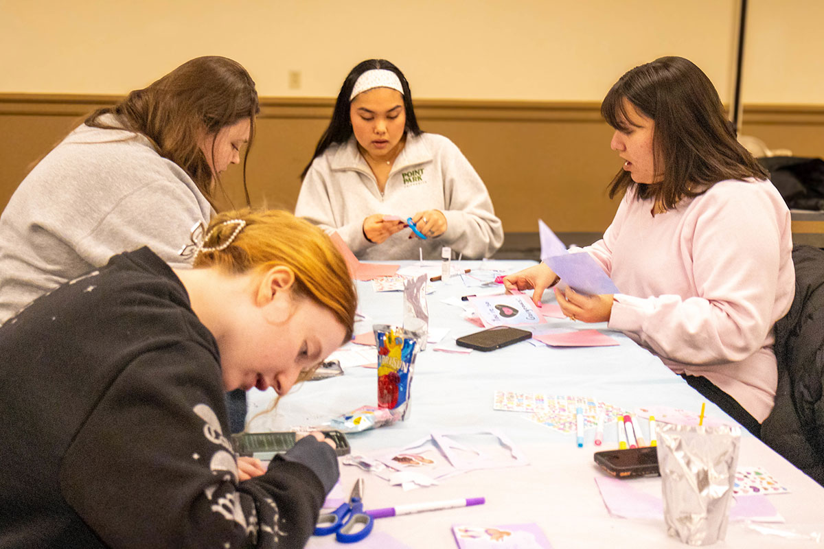 Students sit around a table decorating Valentine's cards.