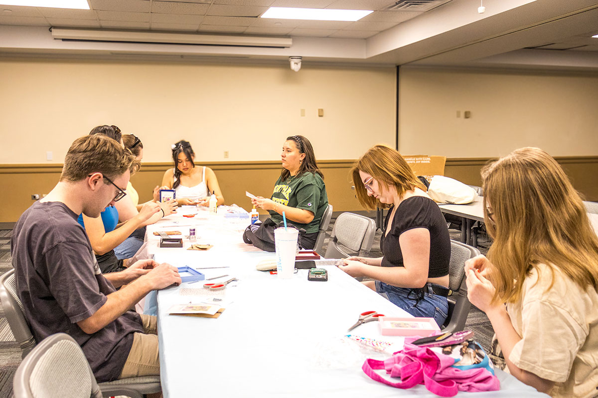 Students sit around a table and decorate picture frames.
