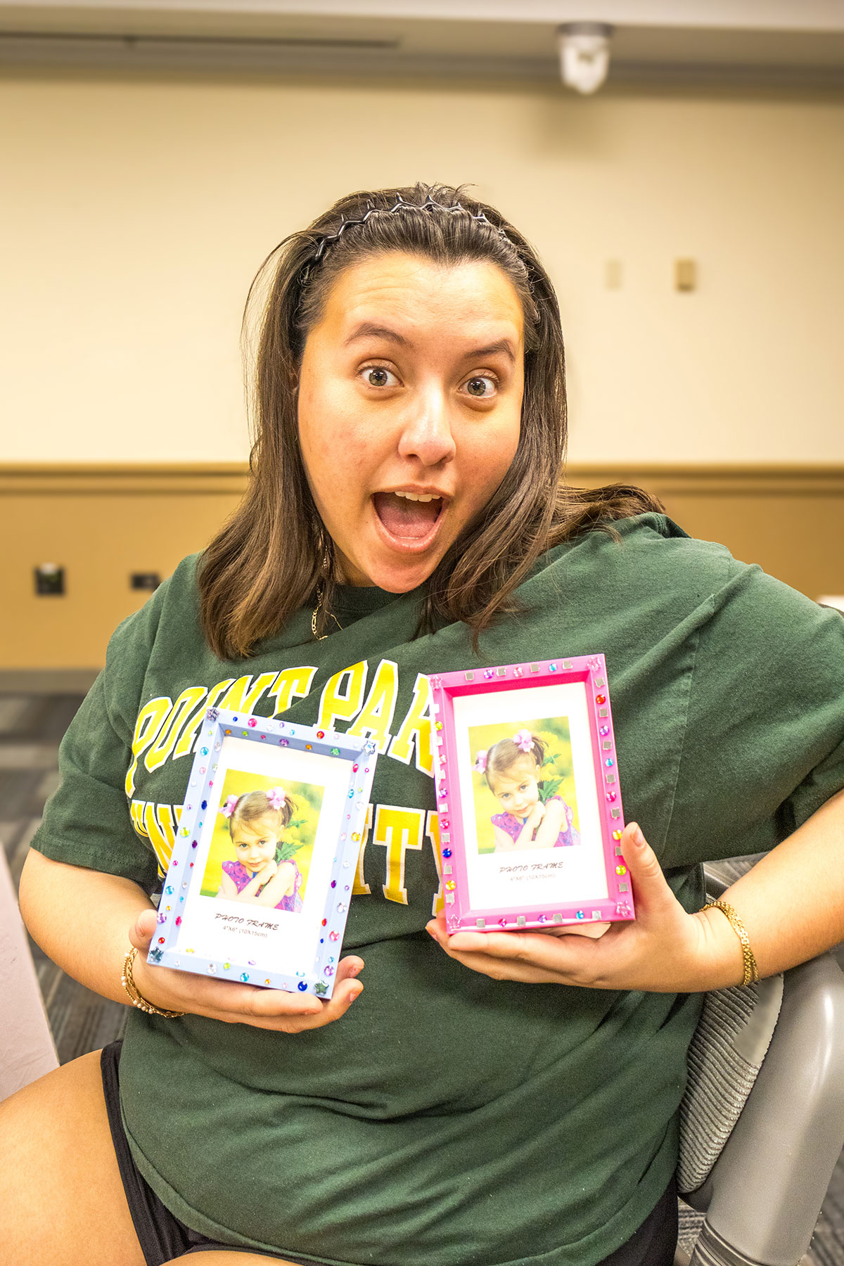 A student holds up her decorated picture frames.