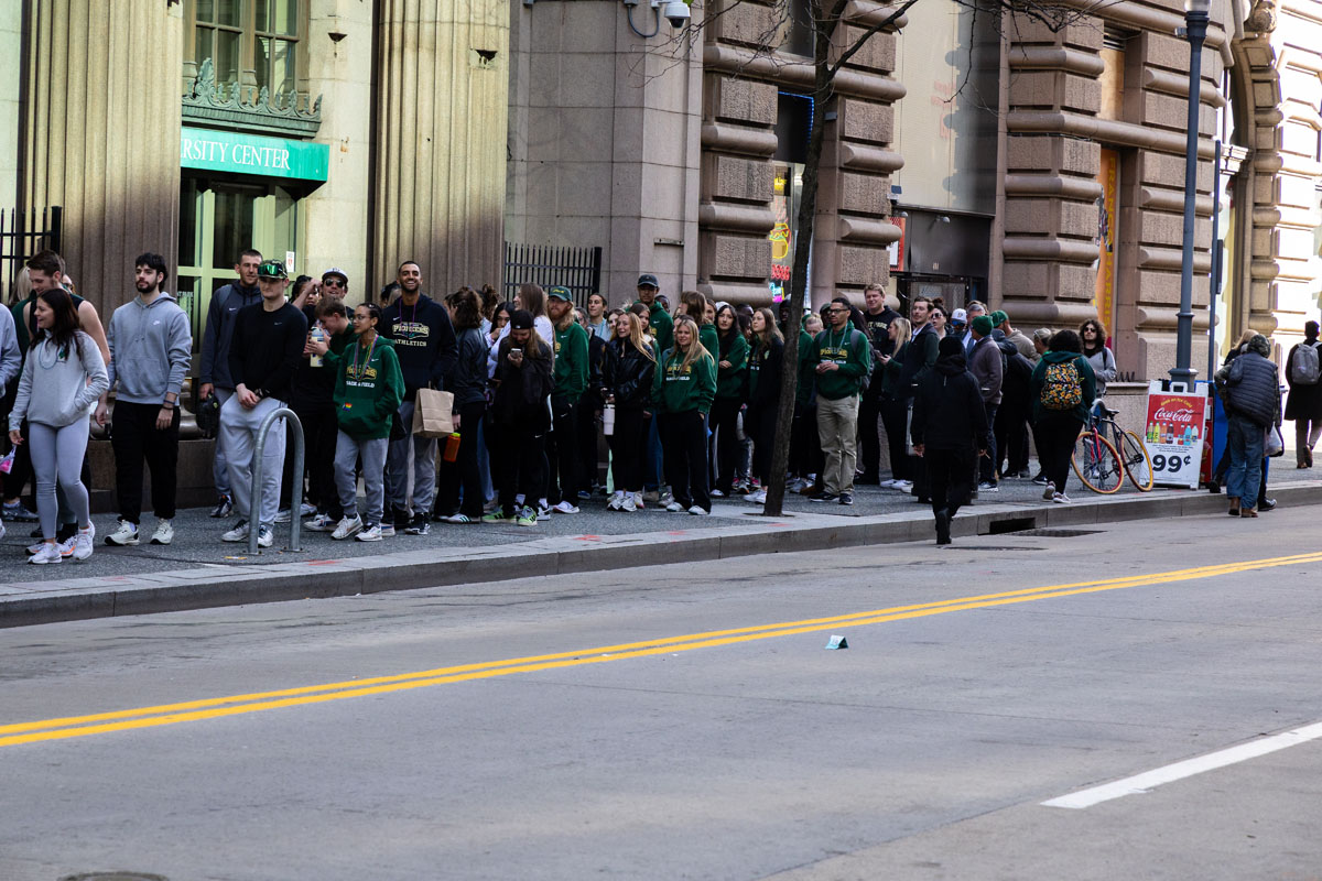 A throng of people walk along the sidewalk on Wood Street.