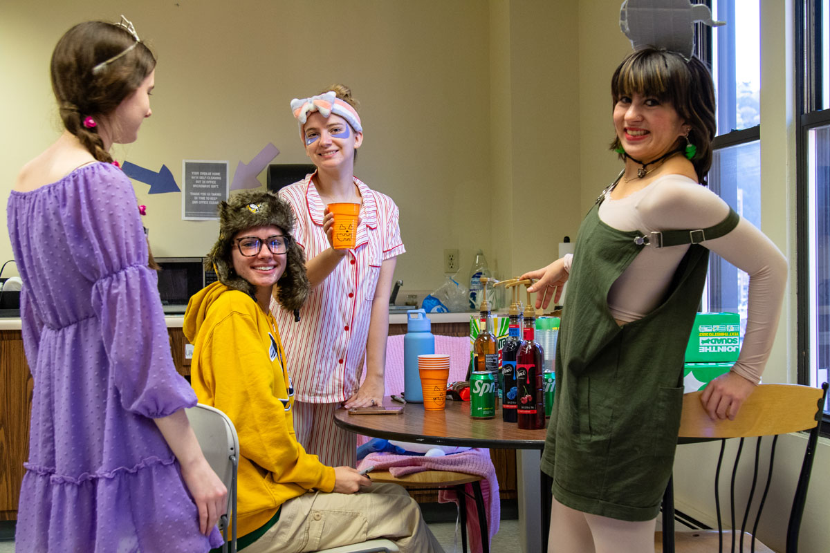 Students dressed in costumes mix up a mocktail.