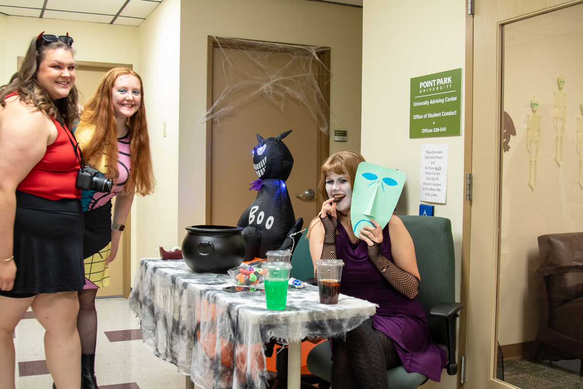 Students dressed in costumes smile at the camera.