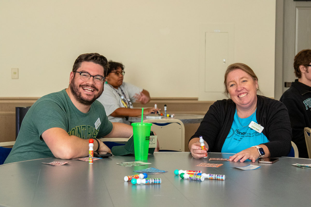 Two staff members smile from their bingo table.