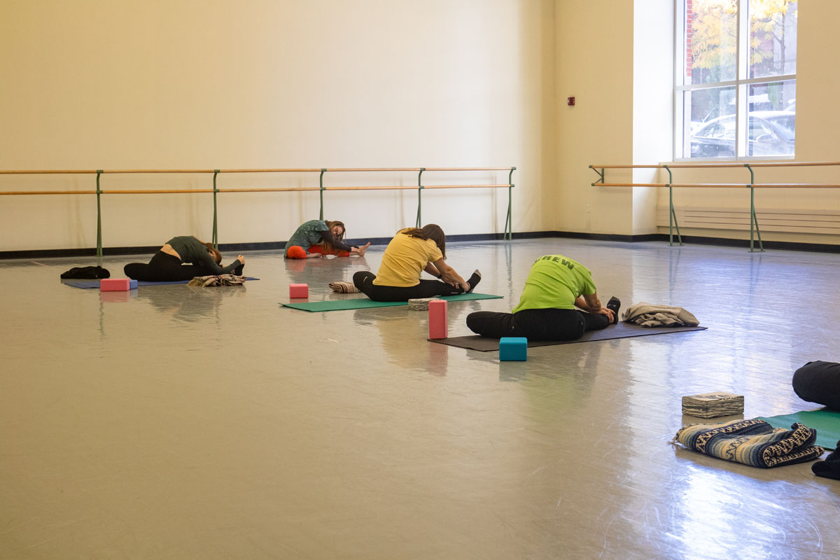 People do yoga in the dance studio.