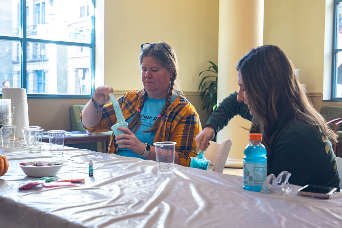 People make slime in plastic cups at a table.