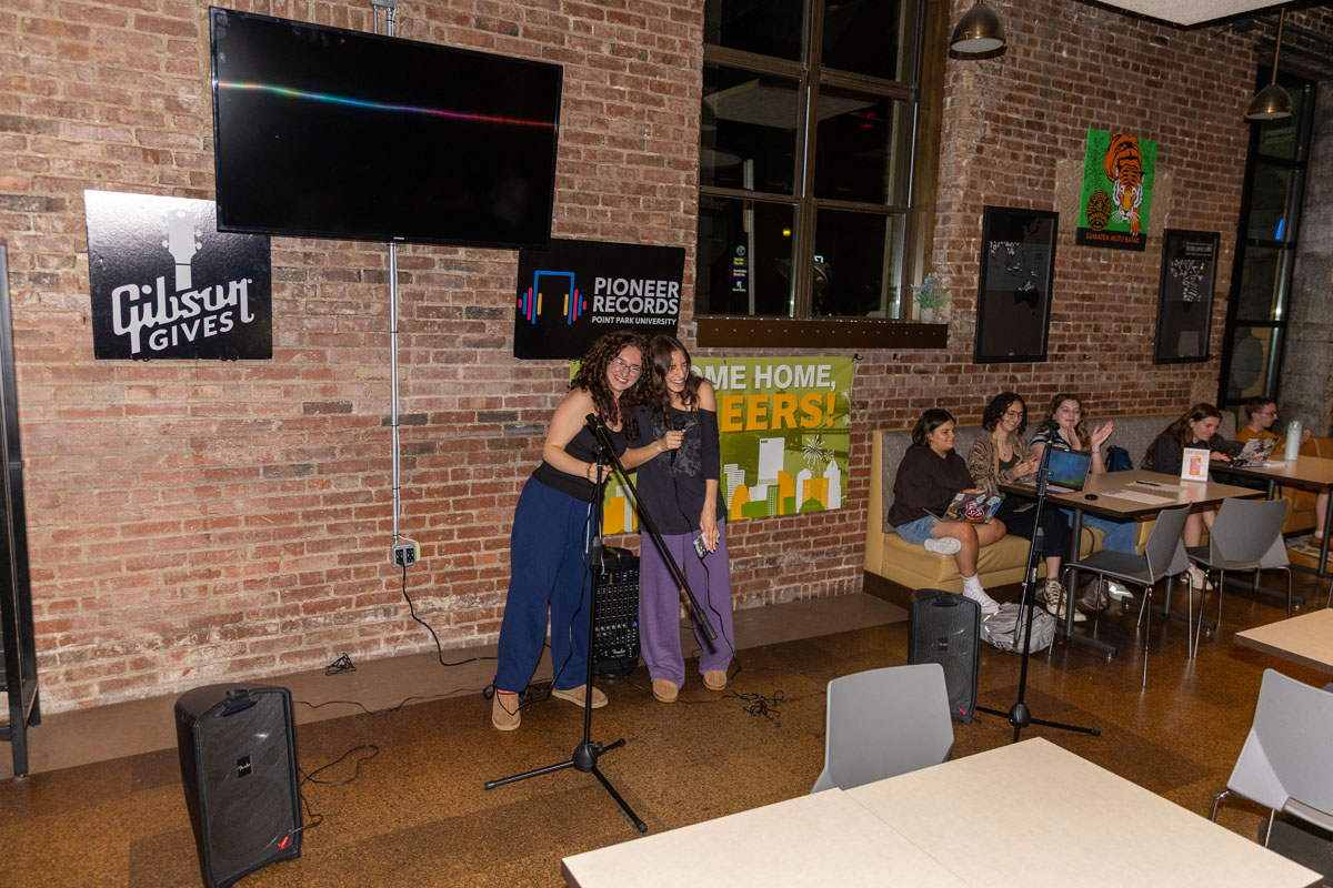 Two students perform karaoke in Bison Bites and Brew.