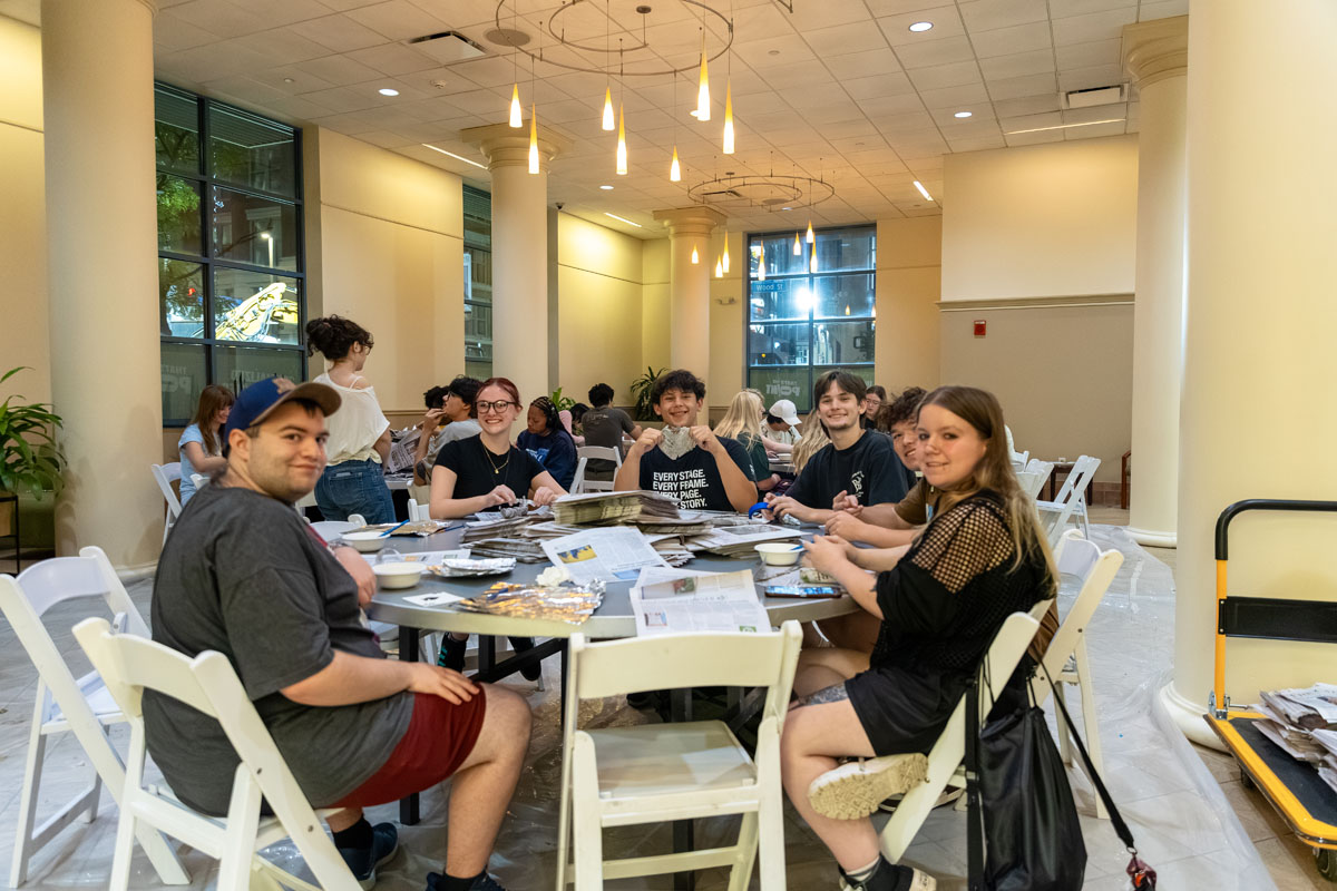 Students sit around tables doing an activity in Lawrence Hall Lobby.