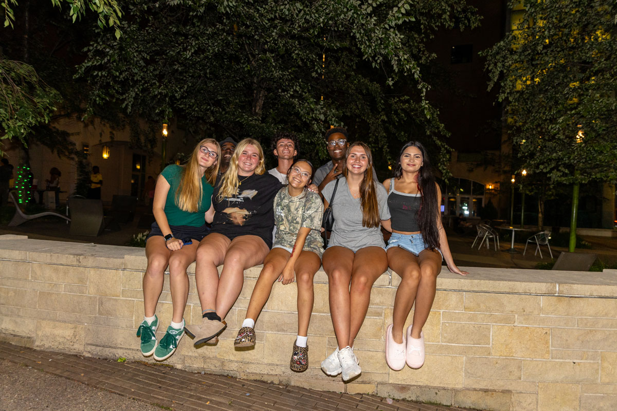 Students sit on a wall in Village Park at night.
