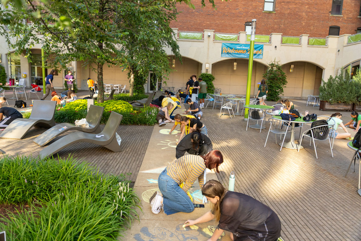 Students draw with chalk on the sidewalk. 