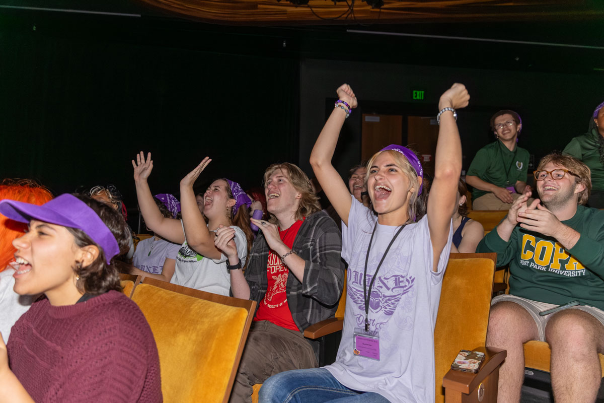 Students cheer from their seats in the theatre.