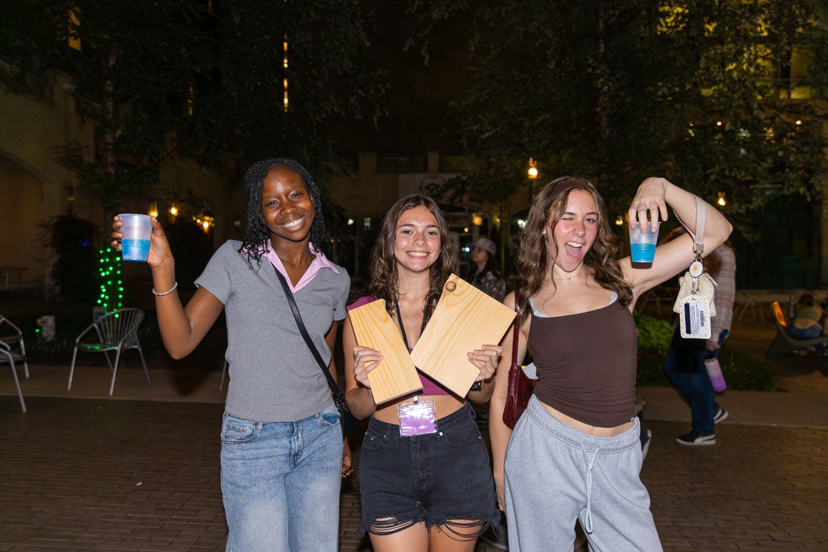 Three students pose for the camera in Village Park at night.