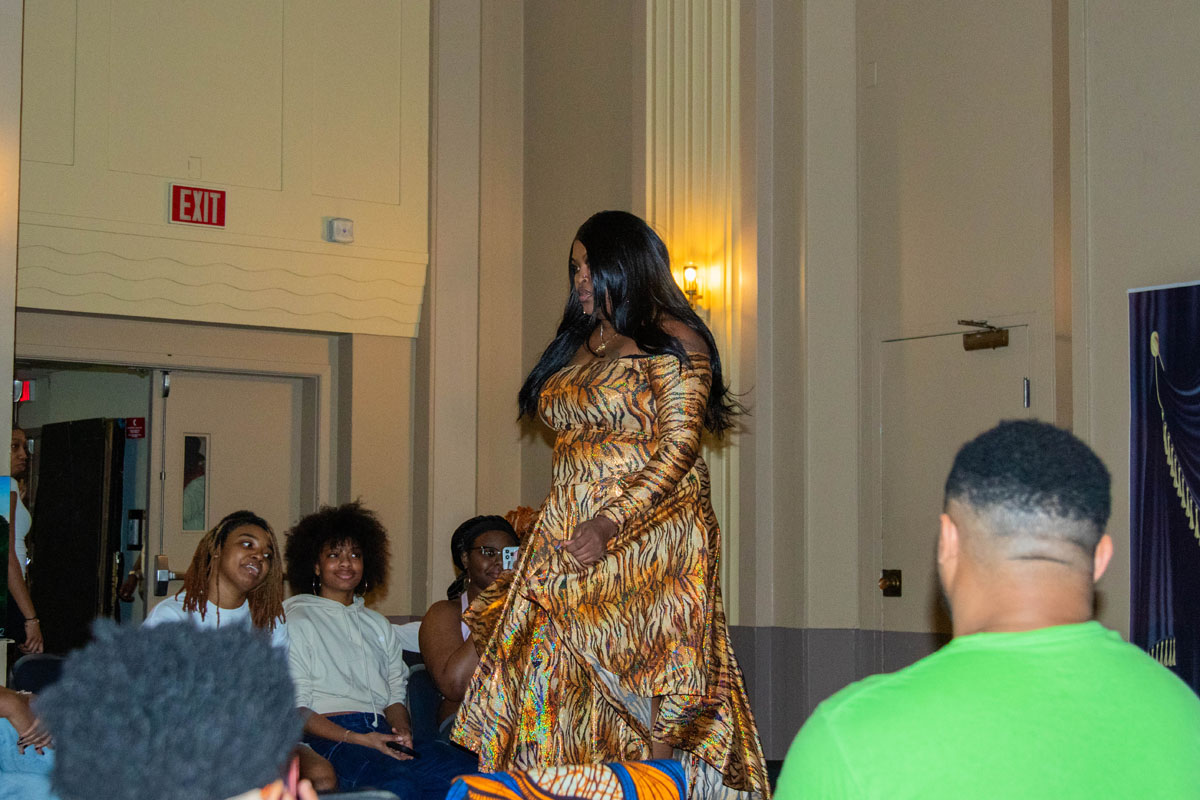A woman walks down the catwalk wearing an iridescent animal-print gown.