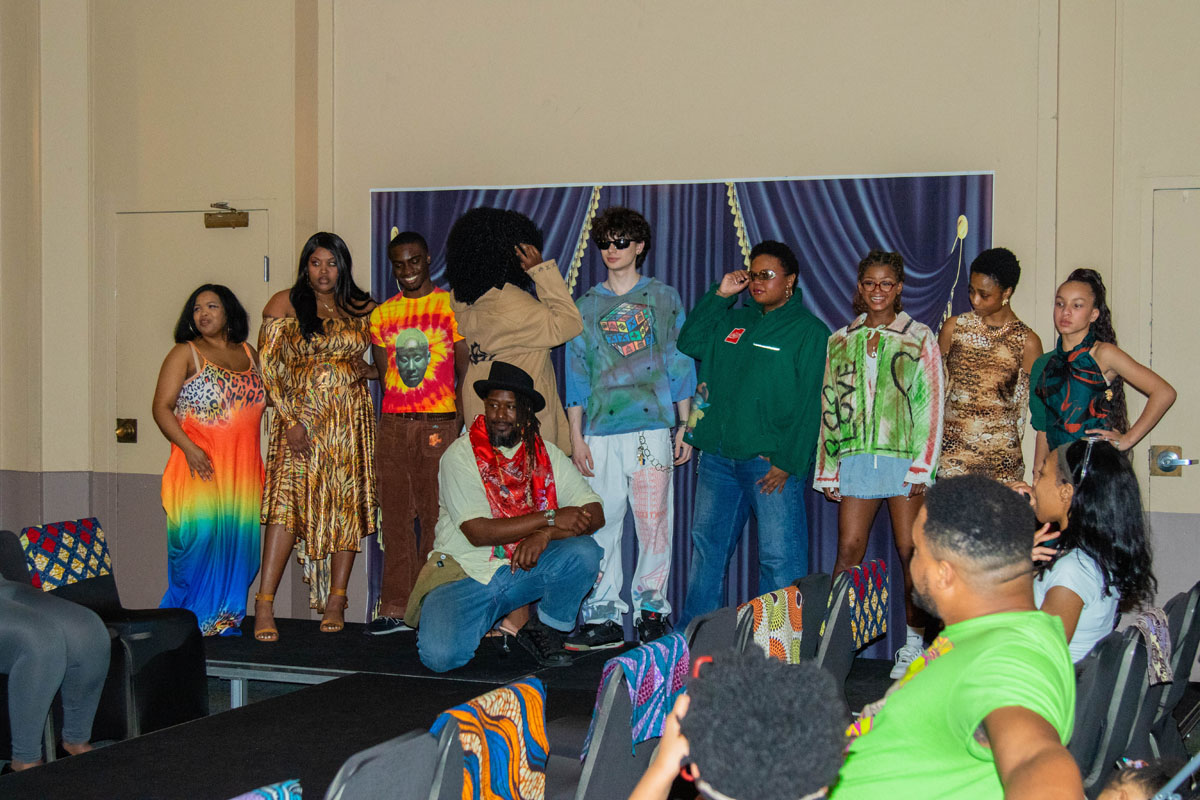 A line of students stand on the stage displaying the fashion.