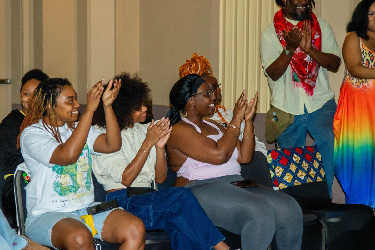 Audience members clap and smile.