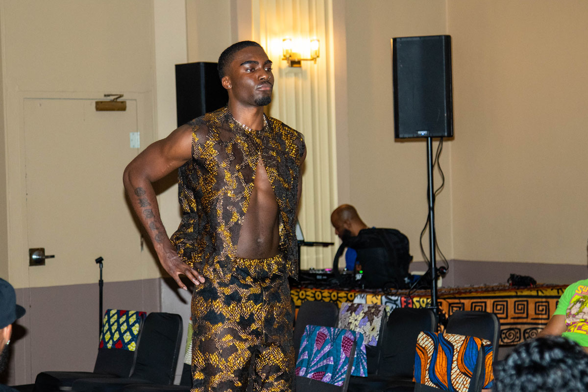 A man walks on the catwalk wearing a snakeskin-print vest and pants.