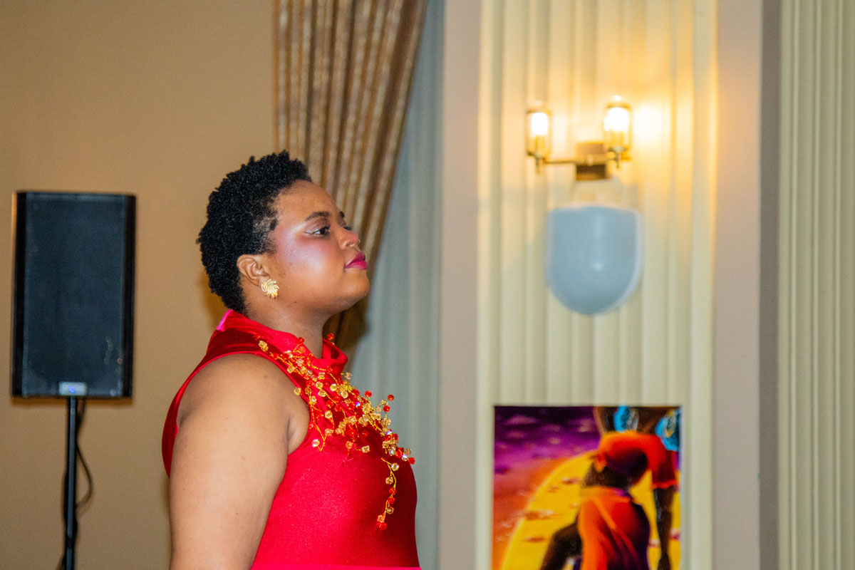 A woman walks on the catwalk wearing a red dress.