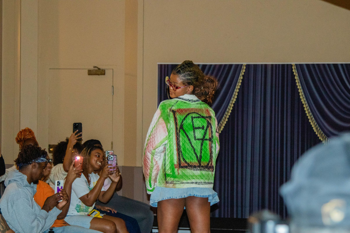 A woman displays the back of a jean jacket that reads "Love."