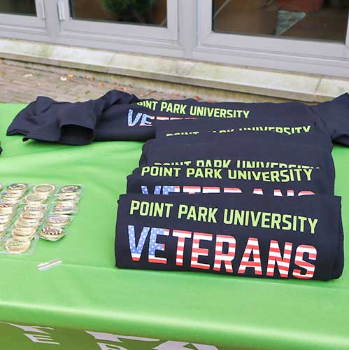 T-shirts that say Point Park Veterans sit on a green table.