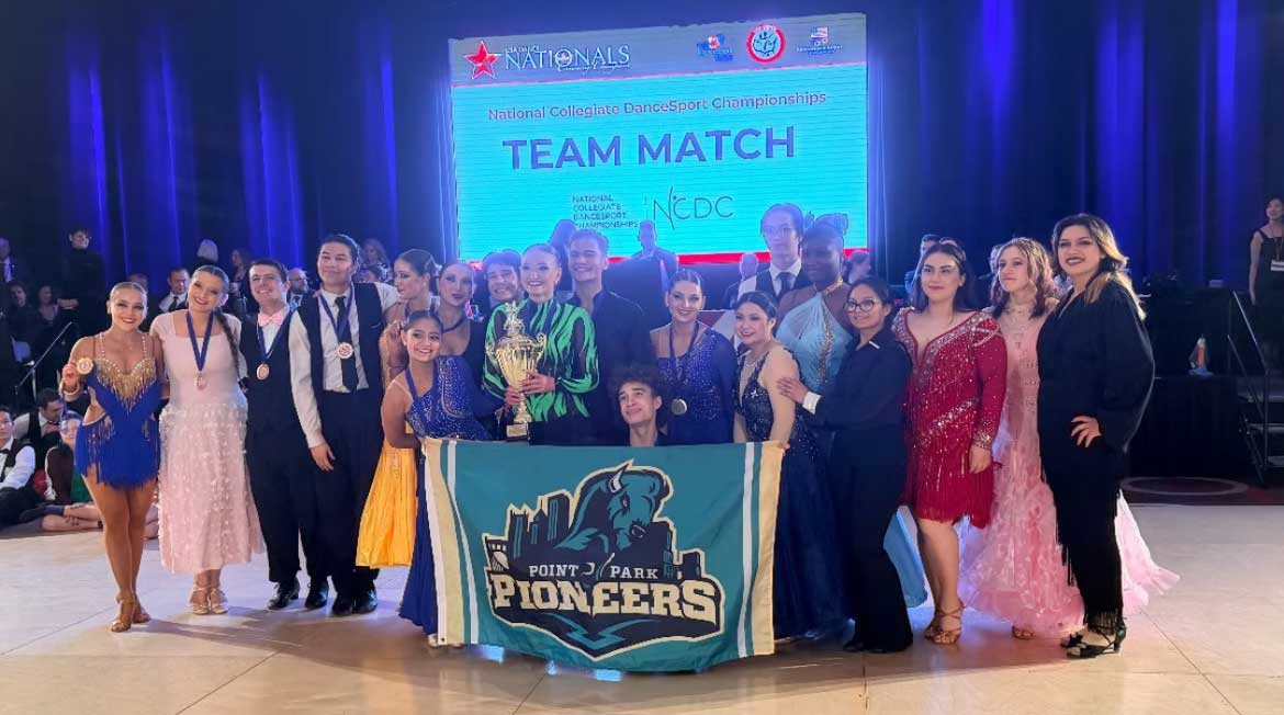 The Dancesport team poses with a banner.