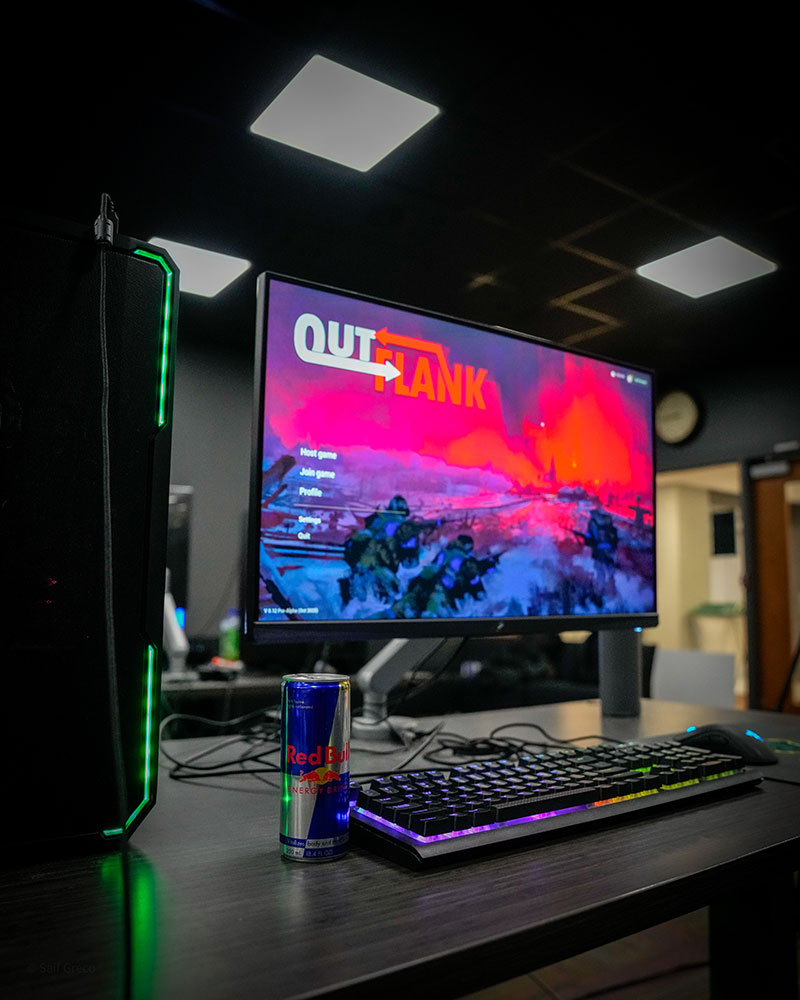 A computer screen with the game image and a Red Bull on the desk. 