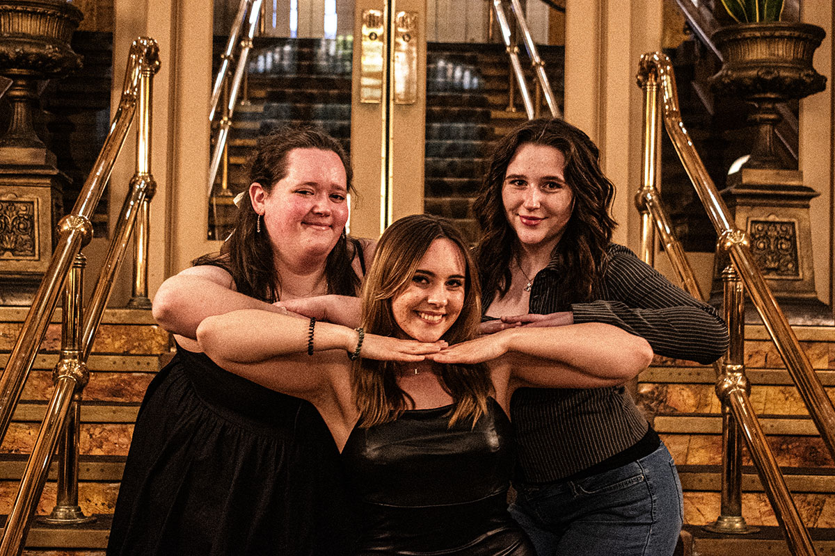 Three students pose for a photo on the stairs of the Grand Concourse.