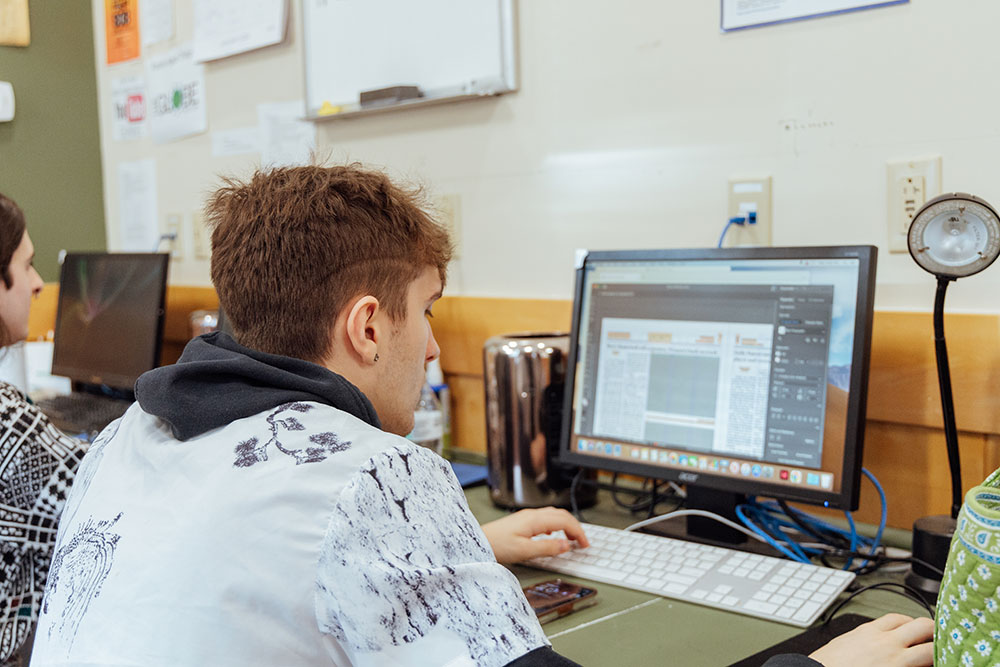 A male student sits at a computer.