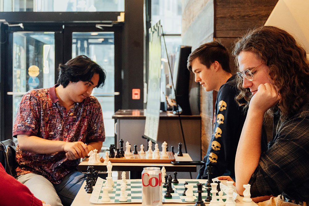 Two chess games are played at side-by-side tables.