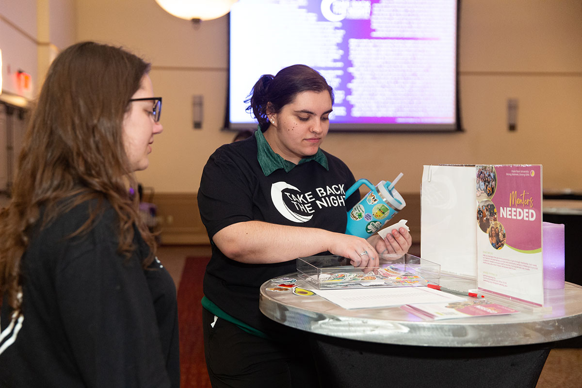 Two students stand at a high top table