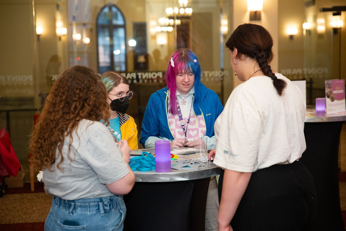 Students stand around a hightop table talking