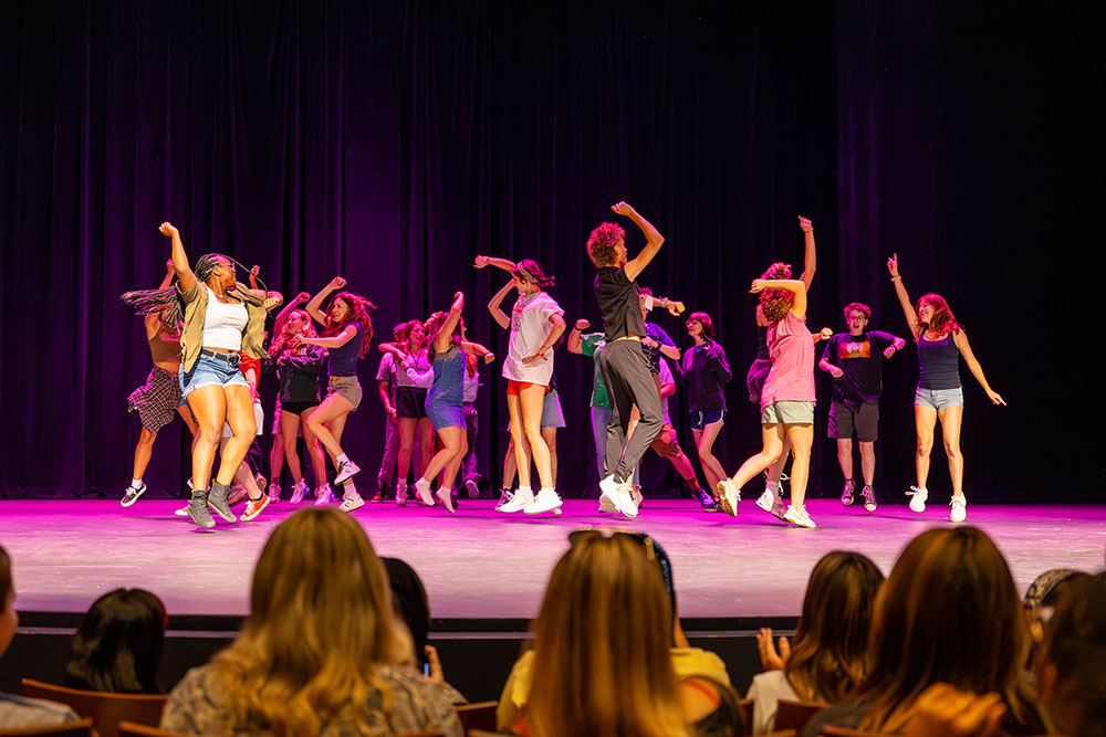 Students dance on stage in a lip sync battle.