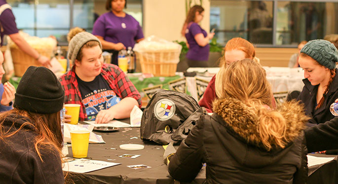 Point Park students sit at a round table decorated in black and gold while playing 412 Bingo, named for Pittsburgh's area code, at the University's first-ever Yinzer Park Feb. 18 in Lawrence Hall. | Photo by Victoria A. Mikula
