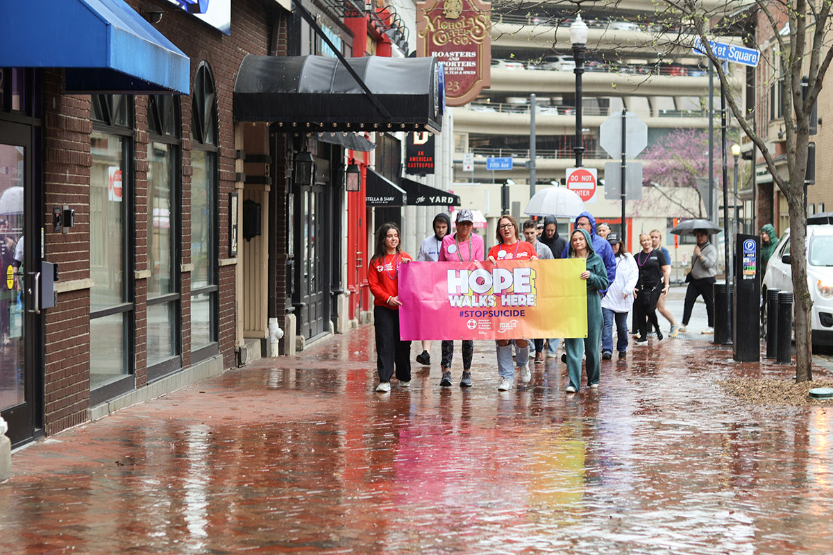 A group of people walk behind the Hope Lives Here sign in Market Square.