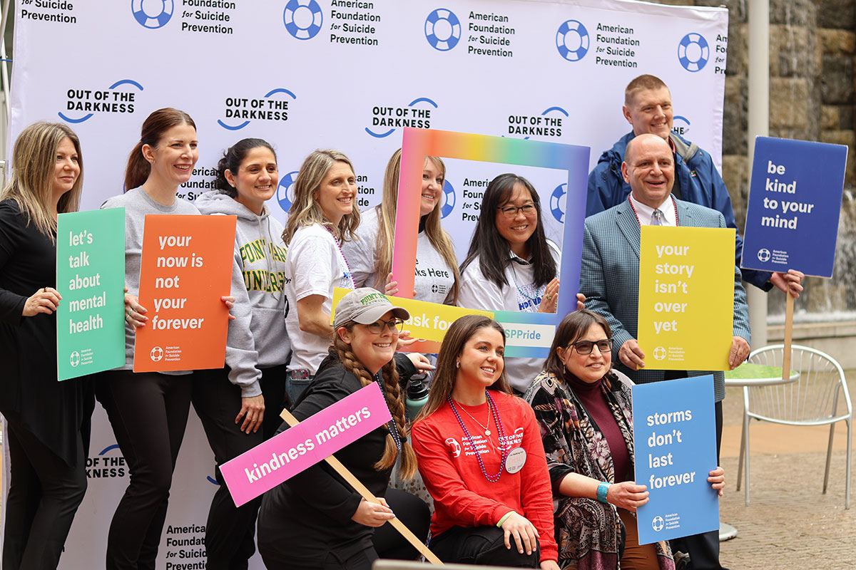 A group of people stand in front of a AFSP sign.