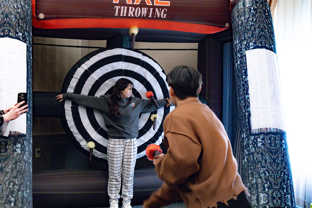 A student stands in front of an inflatable axe throwing bullseye.