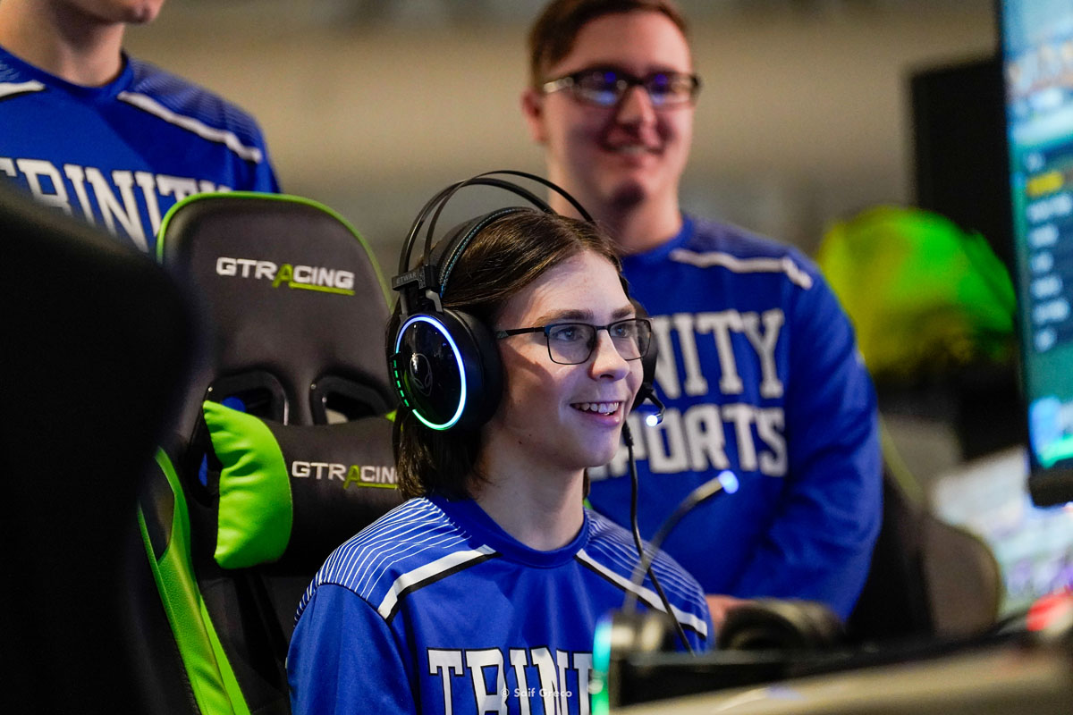 A high school esports athlete smiles at their monitor.
