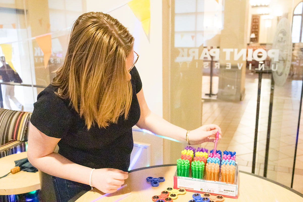 A student chooses a bottle of bubbles from a pack on the table.