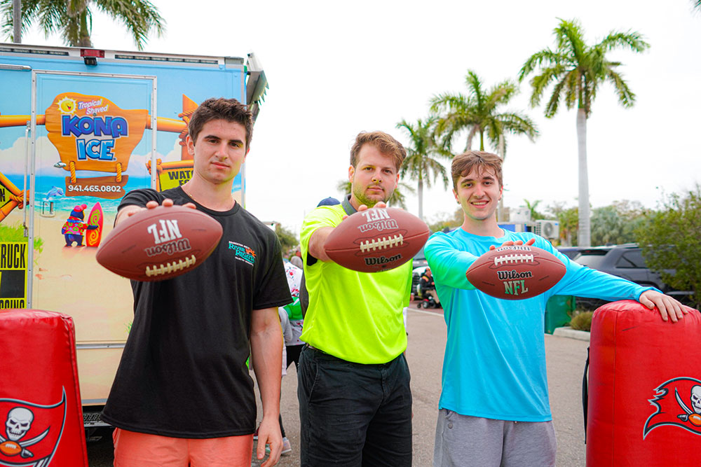 three men hold a football in front of them